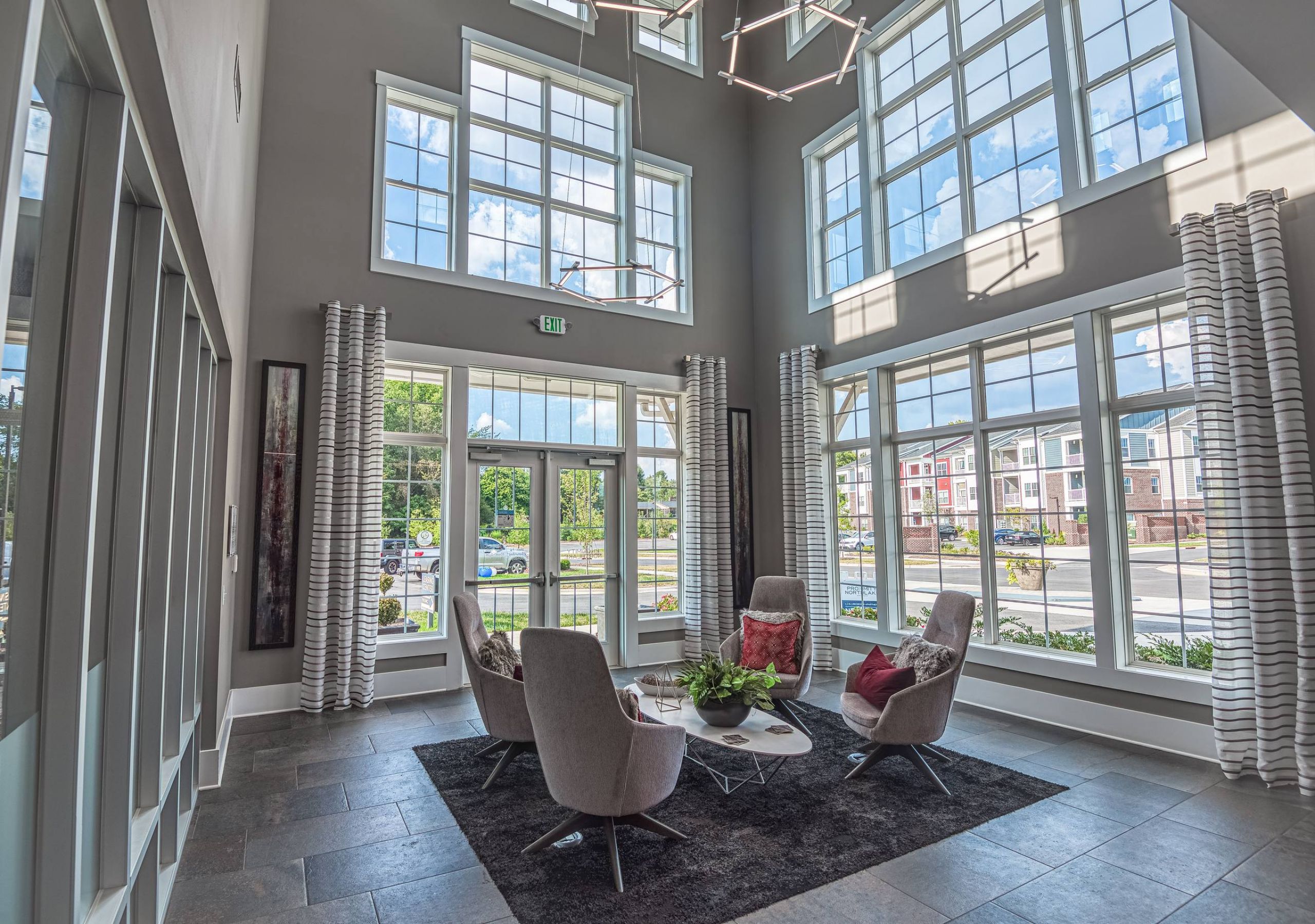 Modern lounge area with four chairs and large windows letting in natural light.