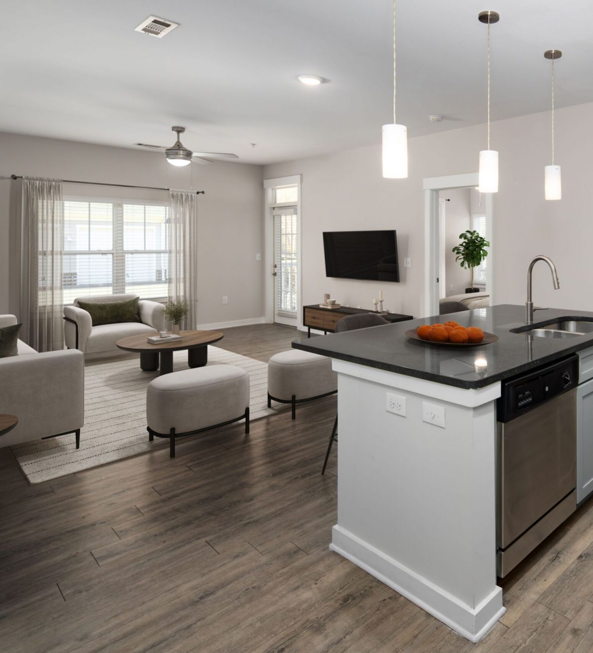 Modern open-concept kitchen and living room with island, pendant lights, and light wood flooring.