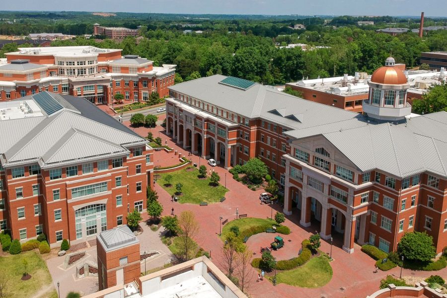 Proximity Northlake Aerial view of a university campus with red brick buildings, walkways, and green trees on a sunny day.