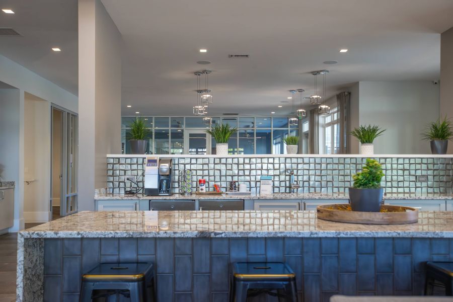Proximity Northlake Modern kitchen with granite countertops, potted plants, and pendant lights above an island with stools.