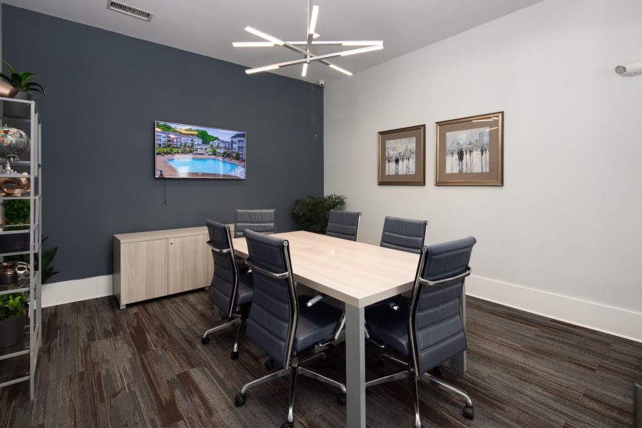 Modern conference room with a rectangular table, six chairs, TV on the wall, and contemporary lighting.