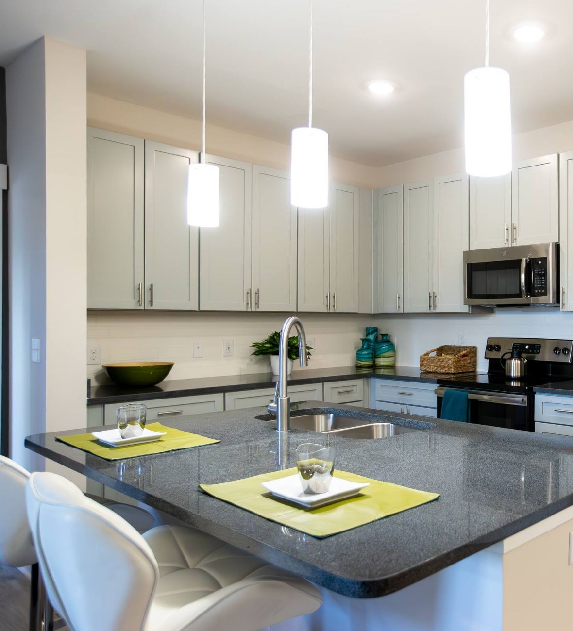 Proximity Northlake Modern kitchen with white cabinets, stainless steel appliances, and a large island with place settings.